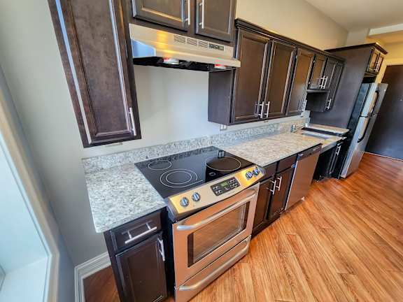a kitchen with dark cabinets and a wood floor