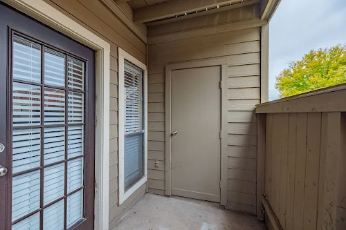 Covered outdoor living space with a concrete patio, privacy fence, and a door to an exterior storage closet 