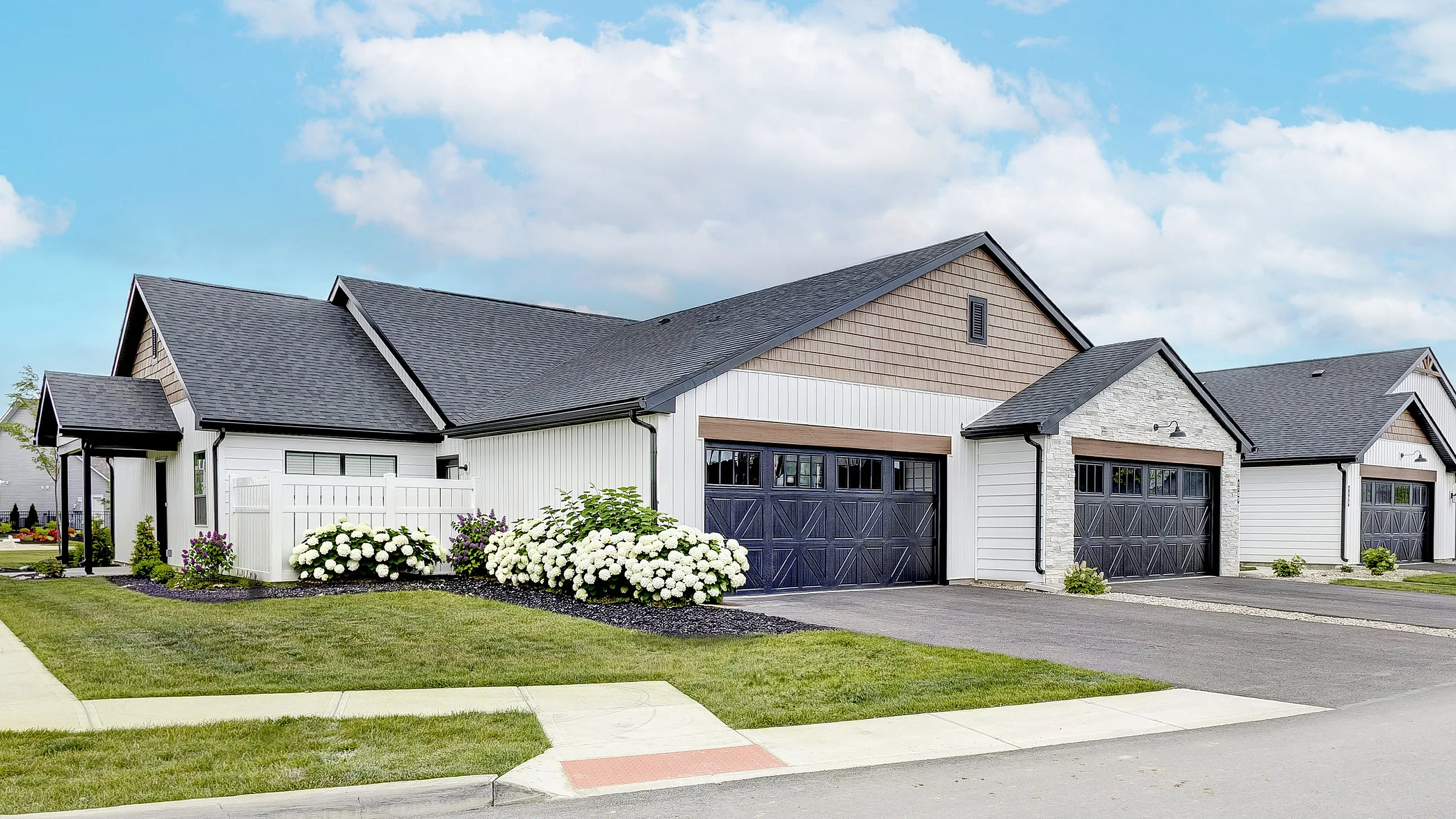 Charming suburban home with a beautiful garden, featuring modern architecture and a spacious double garage under a bright blue sky.