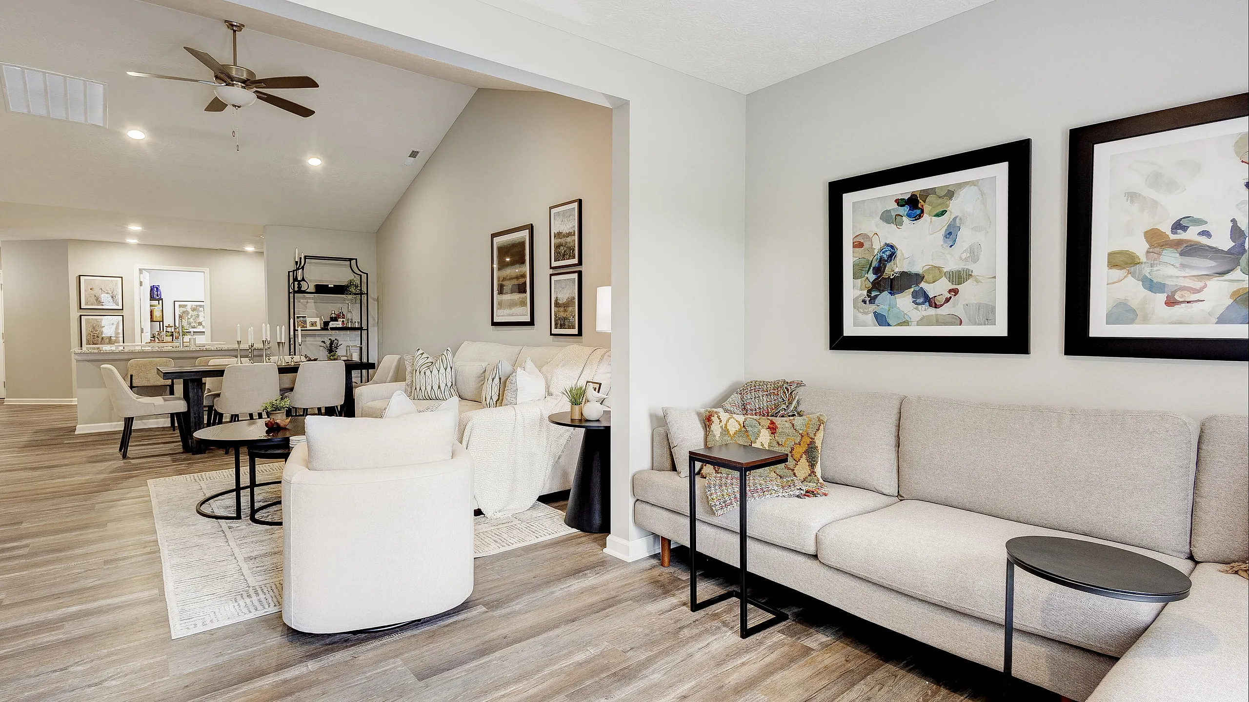 Chic open-concept living and dining area with modern decor, elegant artwork, and warm wood flooring.