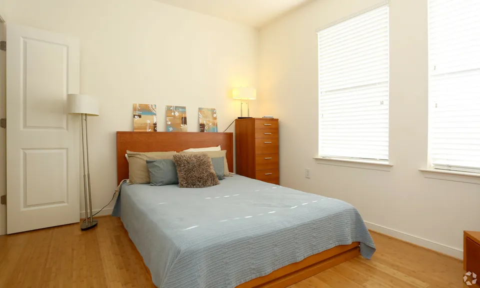 Bright and cozy bedroom with modern decor, featuring a queen-sized bed, tall chest of drawers, and soft ambient lighting.