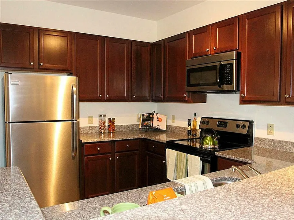 Modern kitchen featuring dark wood cabinets, stainless steel appliances, and granite countertops.
