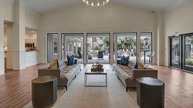 Luxurious apartment community clubhouse lounge area with plush seating, modern coffee table, and lar…