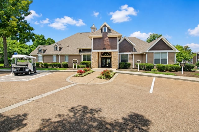 Exterior of apartment building with parking lot and golf cart.