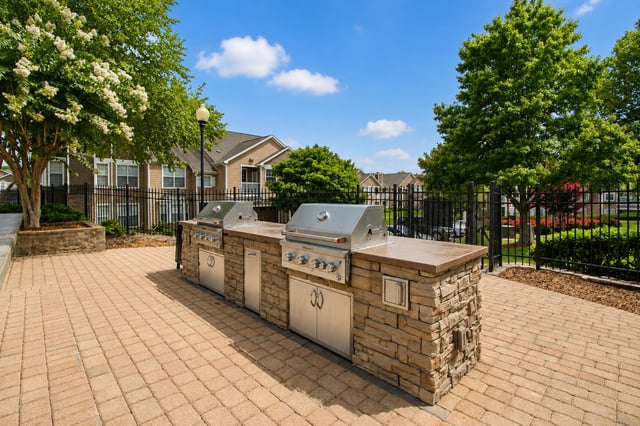 Outdoor kitchen with two built-in grills in a paved courtyard.