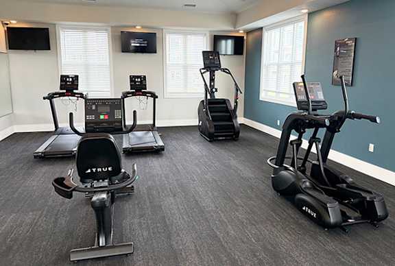A spacious gym with treadmills, elliptical machines, and a television at The Grove Apartment Homes, Lincoln, NE 68512