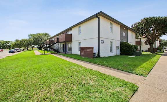 A white apartment building with a green lawn in front.