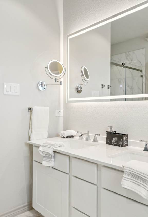 A white bathroom with a sink, mirror, and shower.