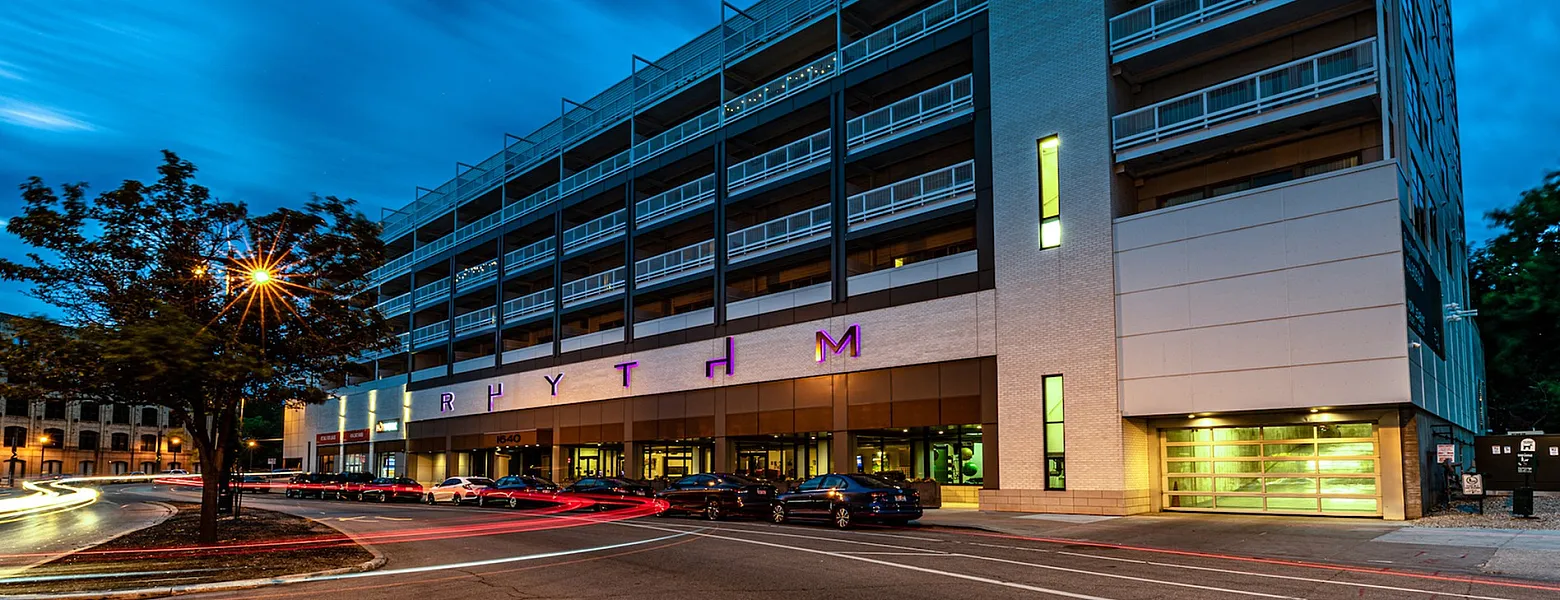 Modern multi-story building with sleek architecture and vibrant exterior lighting at dusk, showcasing stylish urban living.