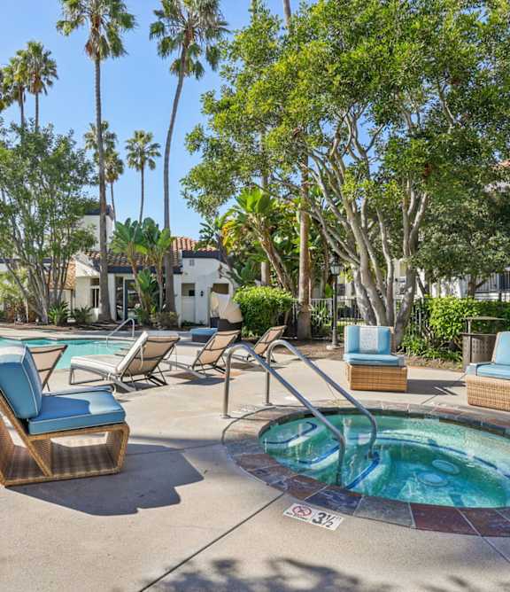 A pool area with a hot tub and lounge chairs.