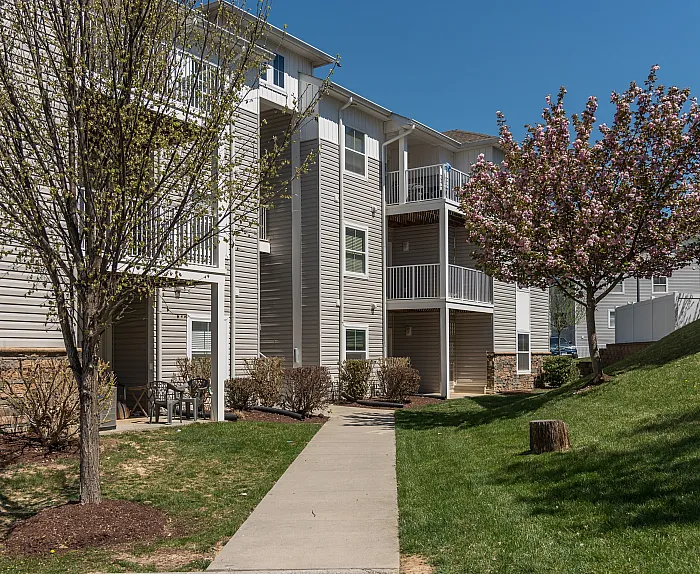 Charming apartment building with modern exterior, lush greenery, and blossoming trees creating a welcoming atmosphere.