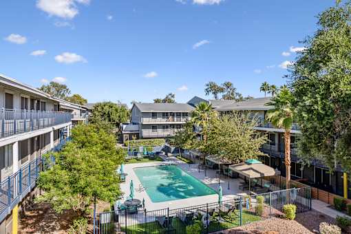 A pool surrounded by trees and apartment buildings.