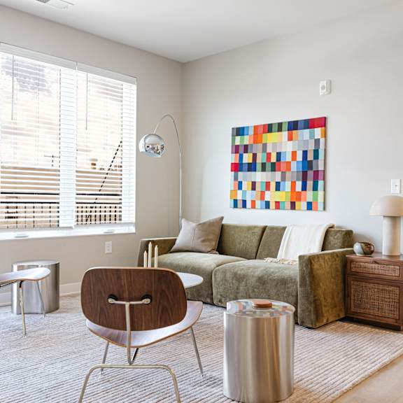 A modern living room with a green couch and a colorful abstract painting on the wall.